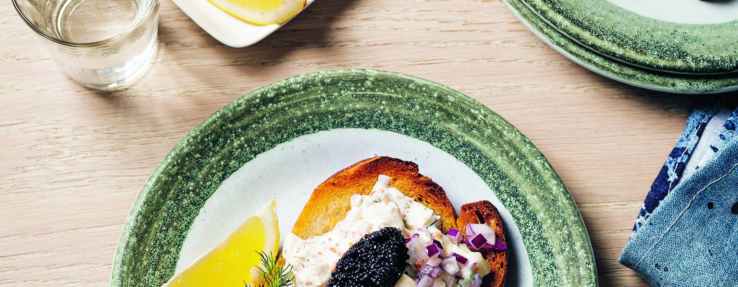 Skagenröra på toast på två tallrikar på ett ljust träbord