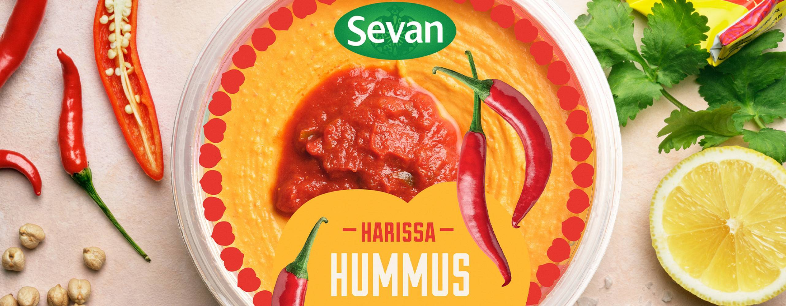 En burk med hummus på ett bort med citron, mynta, vitlök och kikärtor runt