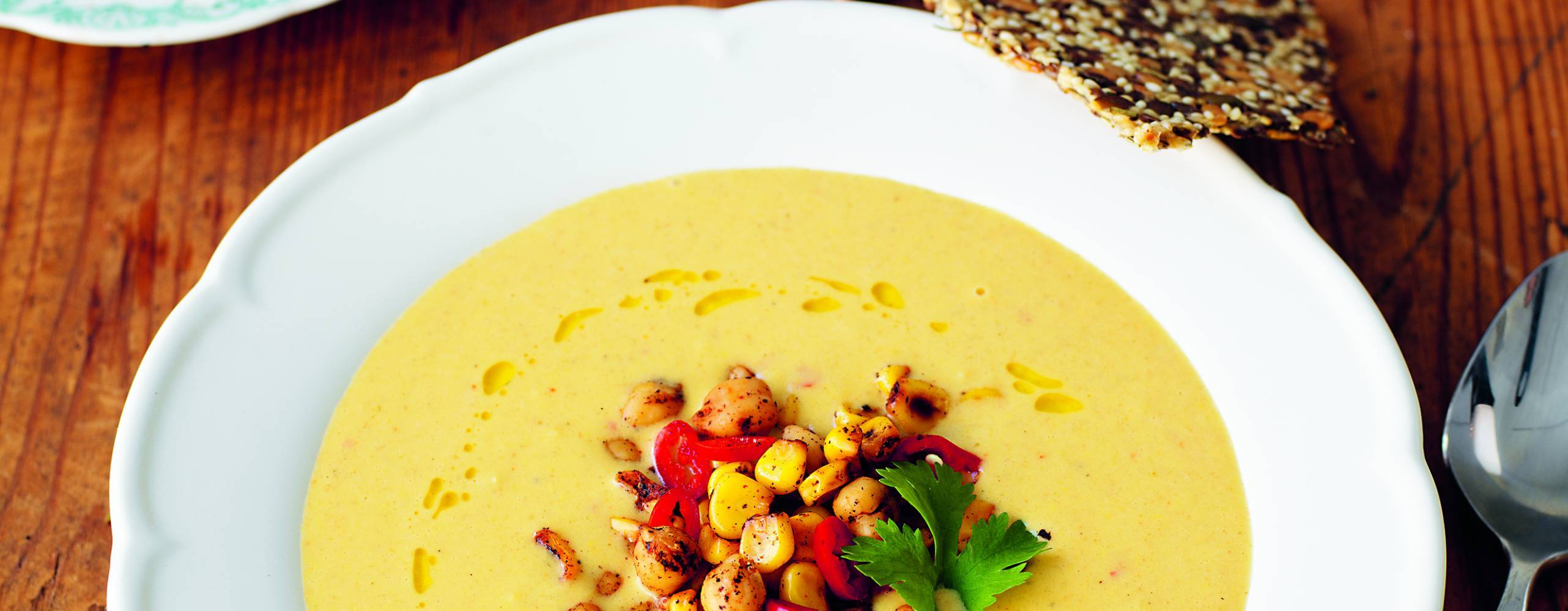 Majssoppa på ett träbord med en sked på sidan