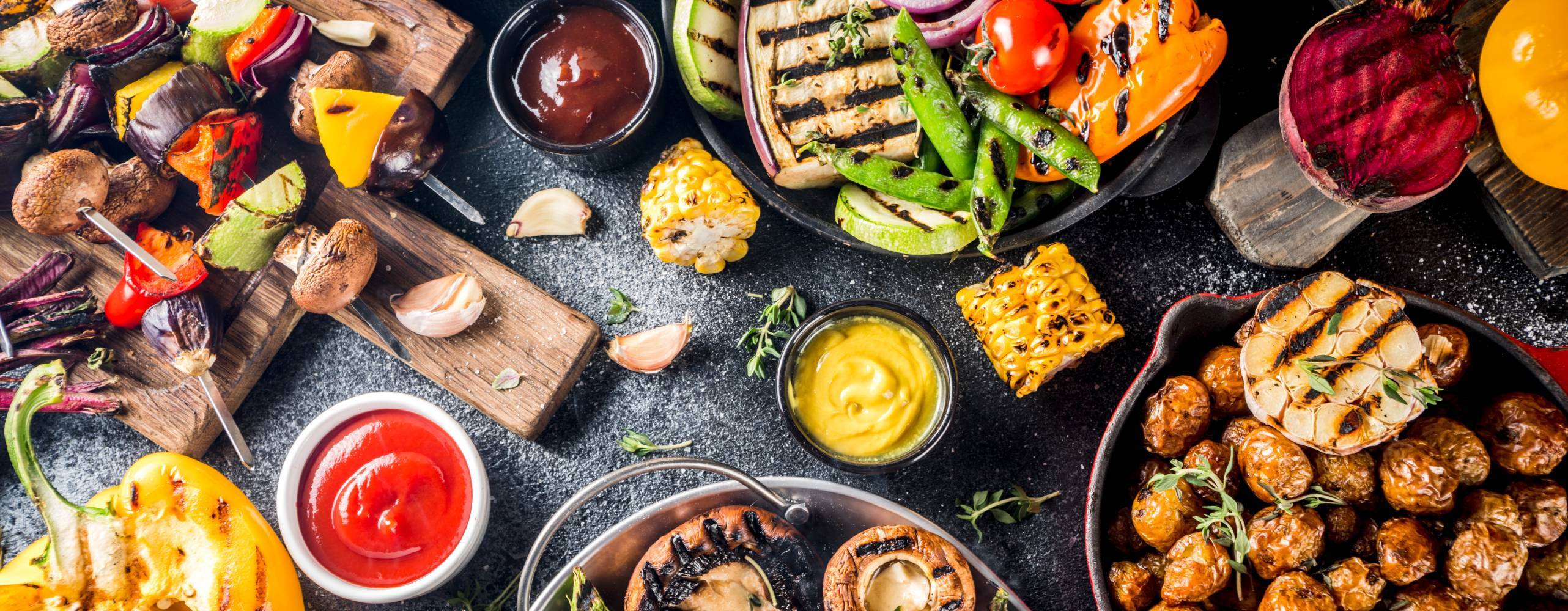Ett bord fullt med grillade grönsaker och veganska tillbehör