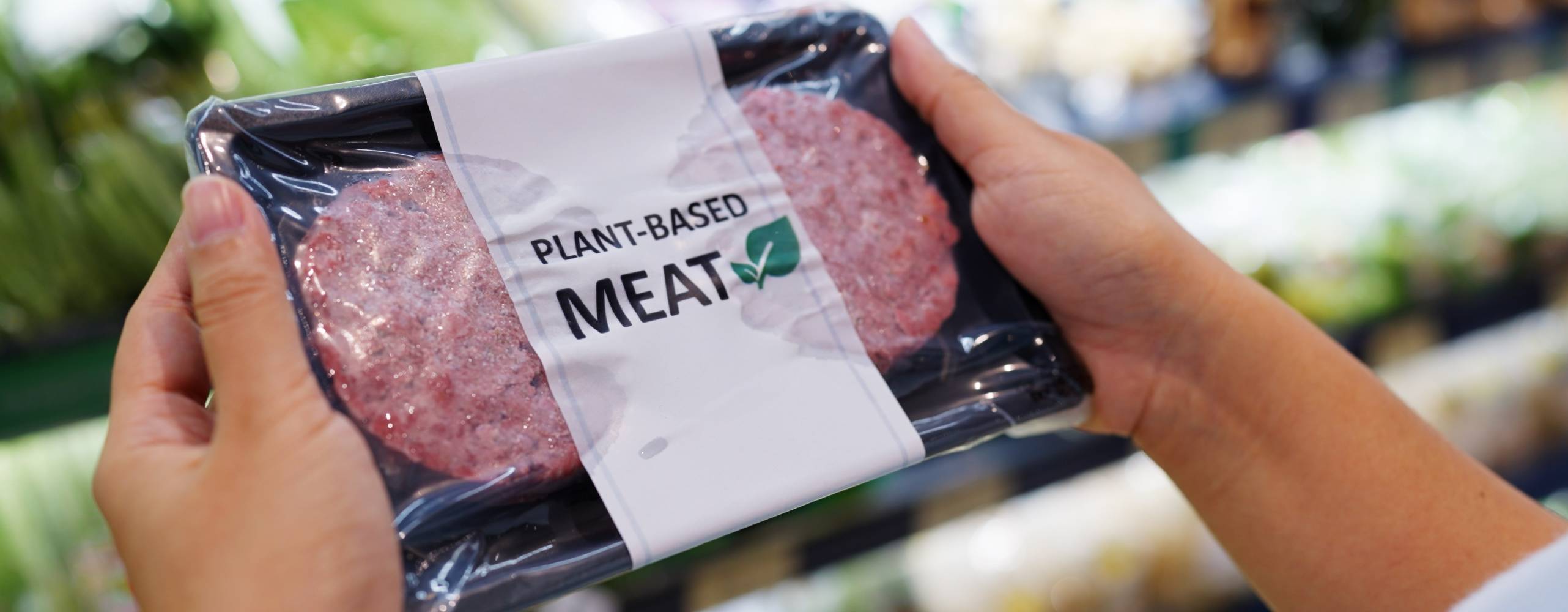Händer som håller i en förpackning vegansk kött i en butik