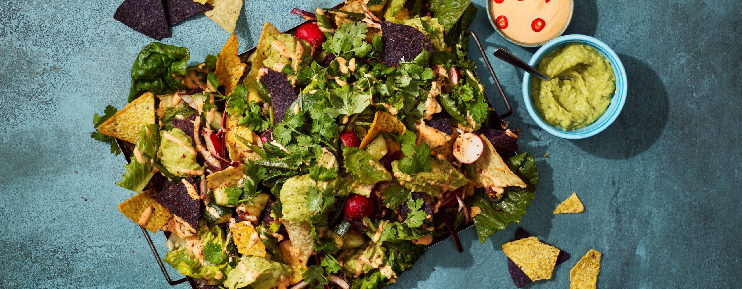 en bricka med nachos och topping på ett mörgrått bord