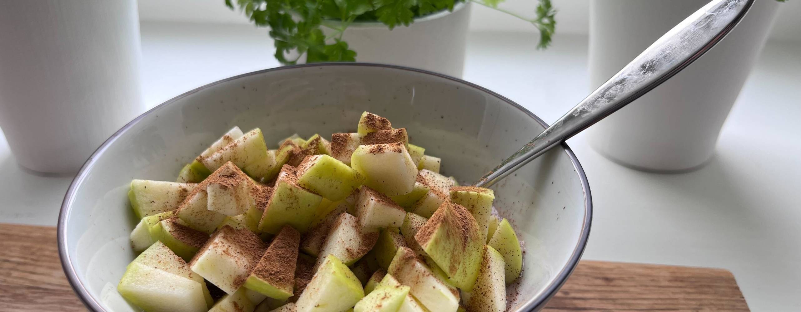 gröt med äpple i en skål på ett träbord