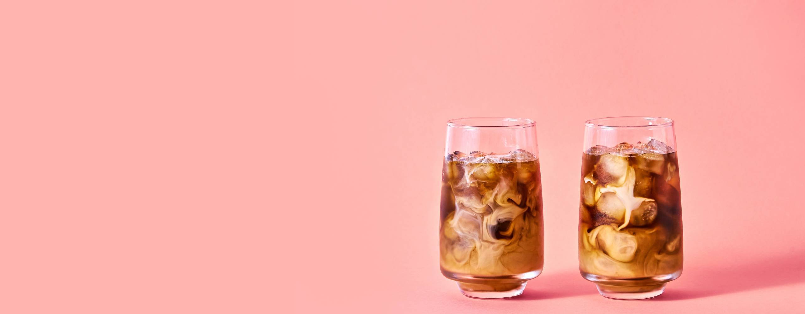 Iskaffe med växtdryck mot en ljusrosa bakgrund