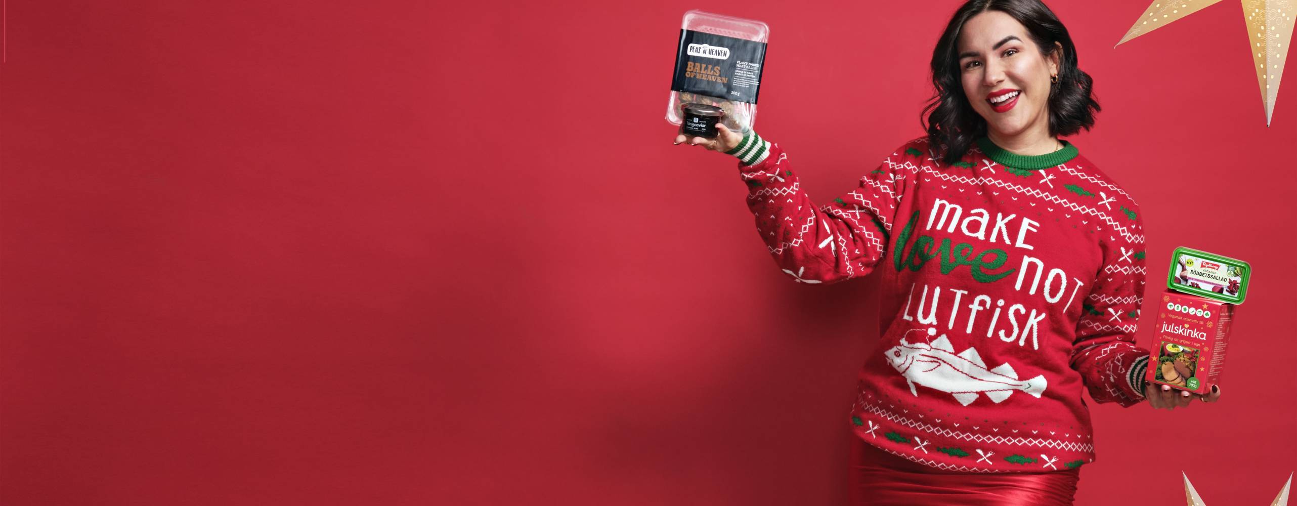 Mörkhårig tjej i röd jultröja mot en röd bakgrund hållandes i julmat