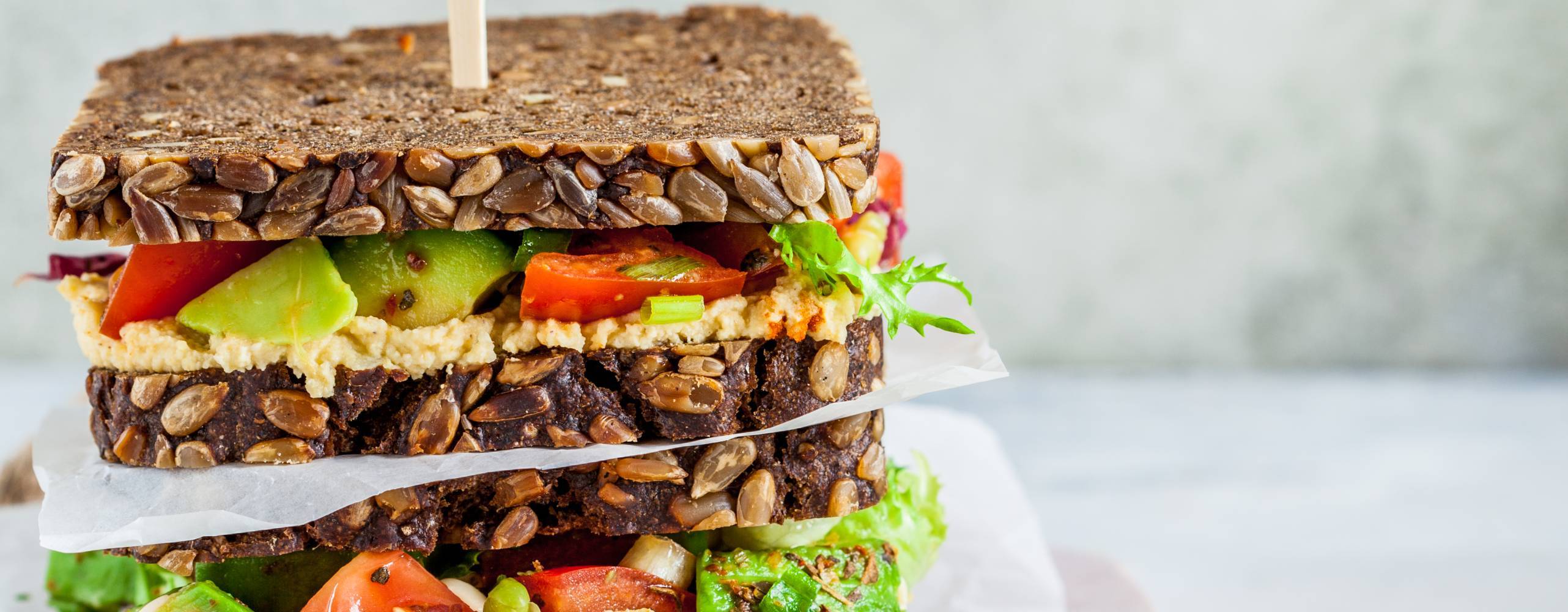 Veganska mackor med hummus, tomat, avokado och sallad på fullkornsbröd.