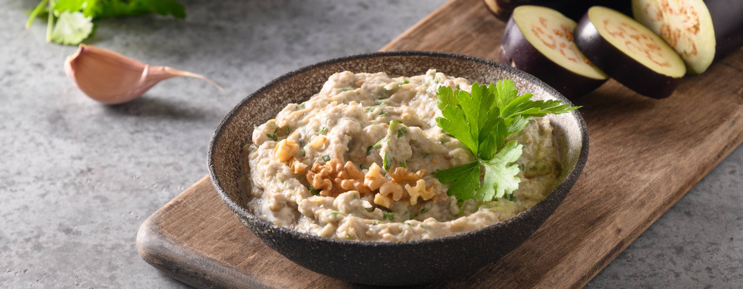 Baba ganoush i en tallrik på en skärbräda.