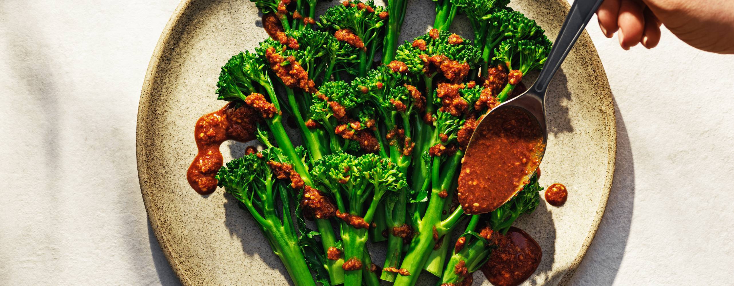 Ångad broccoli på en tallrik med dressing över