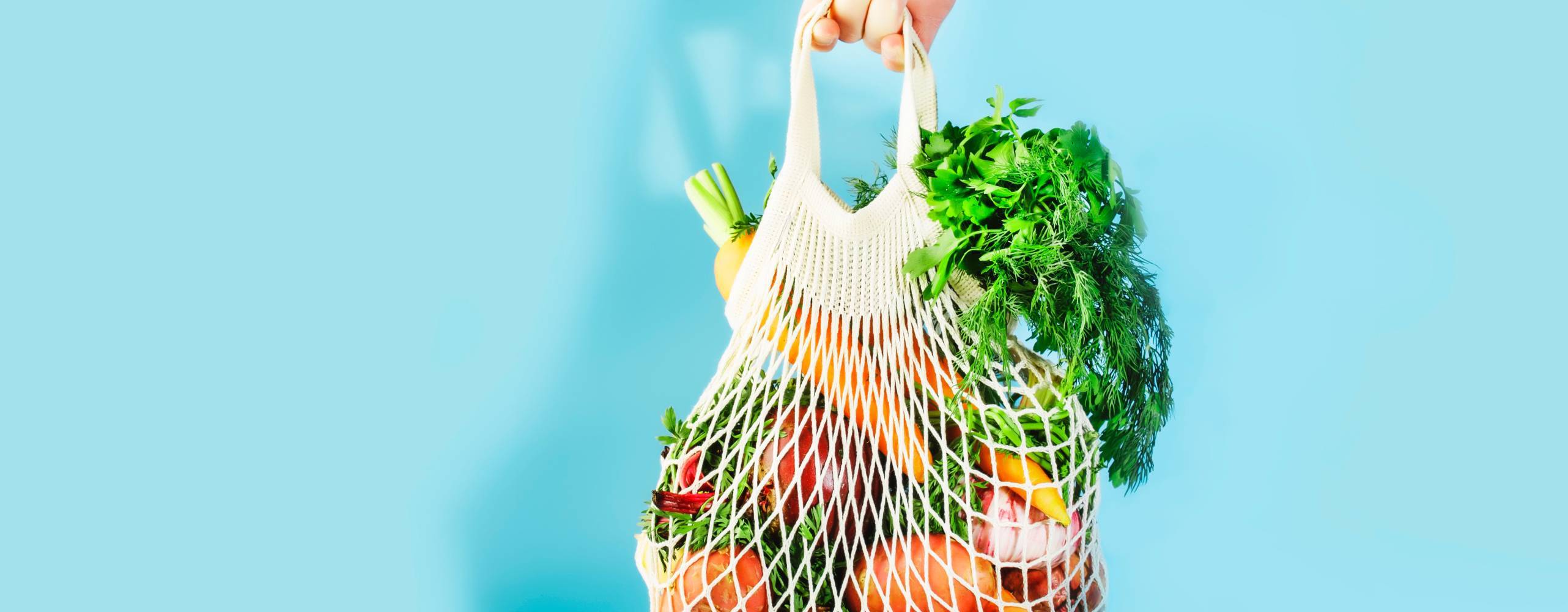 Råvaror i en nätkasse mot en ljusblå bakgrund