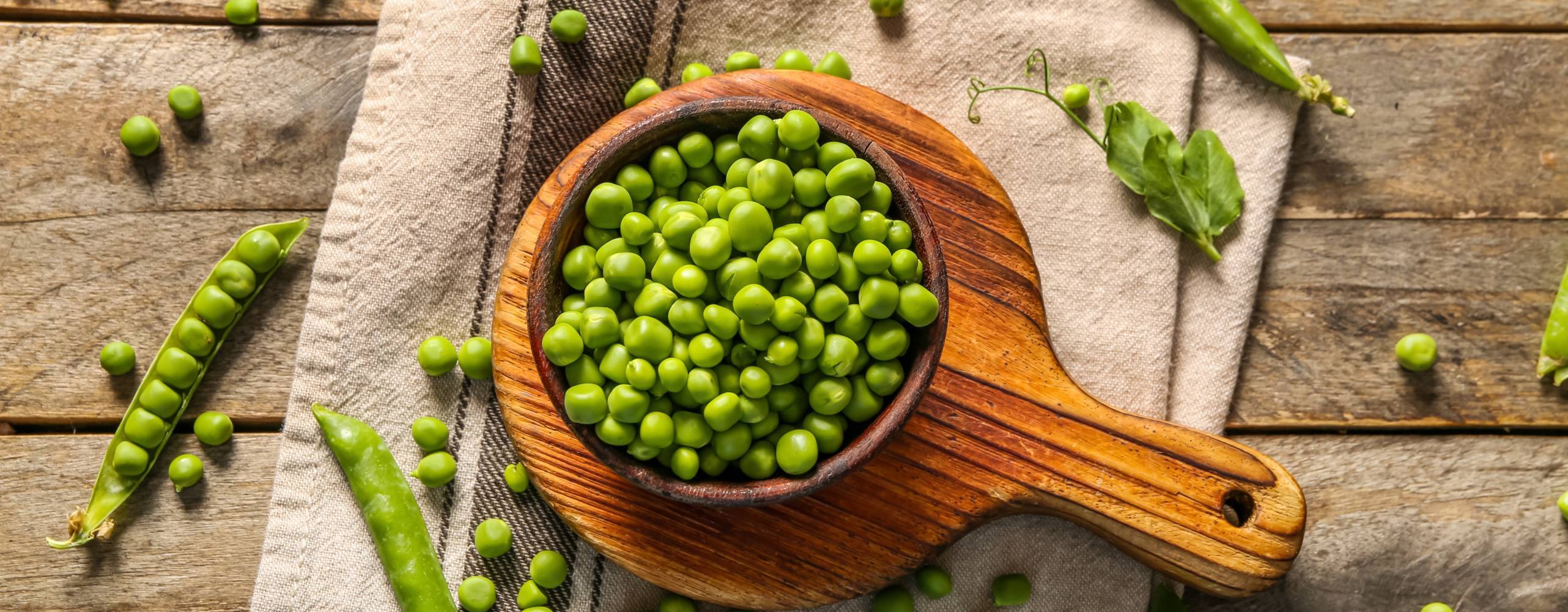 En skål med gröna ärtor mot en träbakgrund