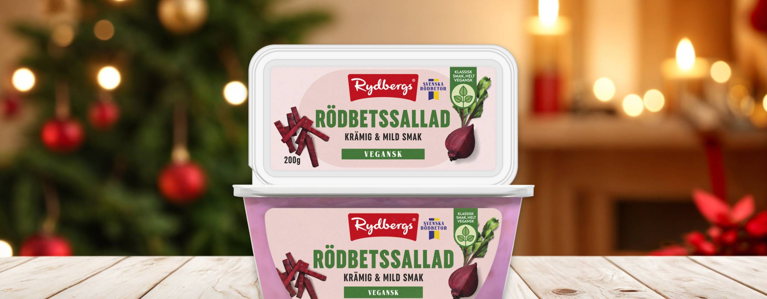 två förpackningar vegansk rödbetssallad staplade på varanda på ett träbord med en julig bakgrund