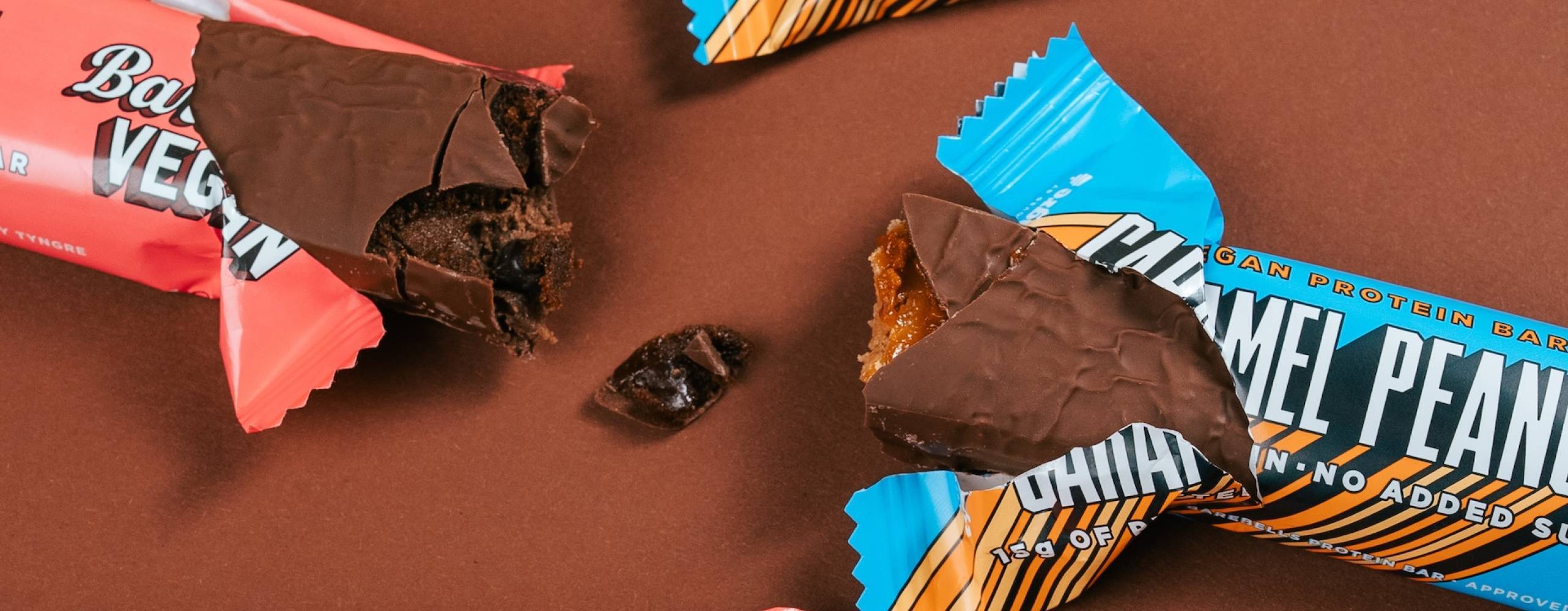 Fyra veganska proteinbars på ett brunt bord