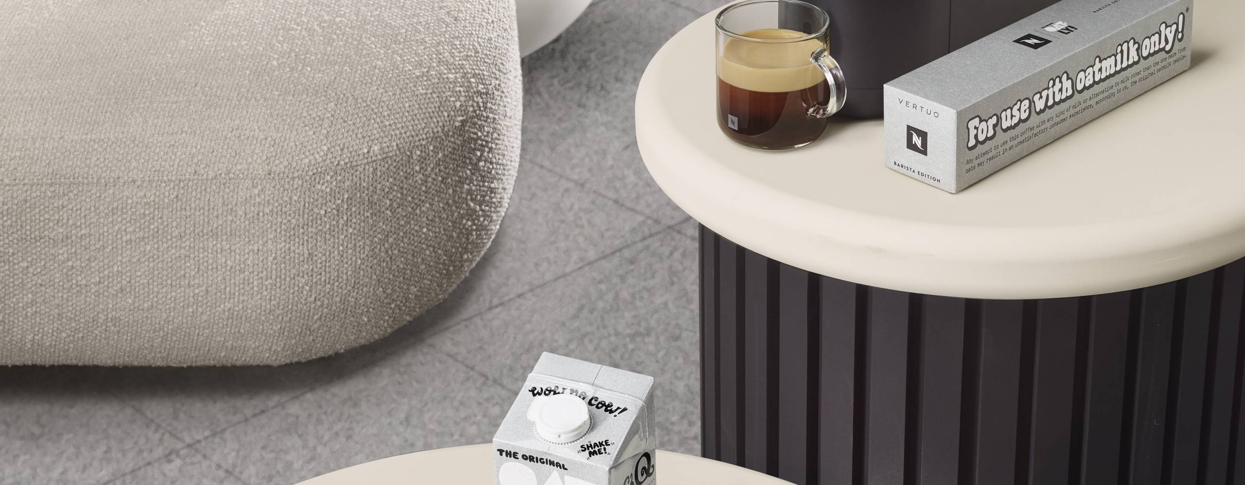 Nespressomaskin på ett bord och oatlyprodukter på ett annat bort