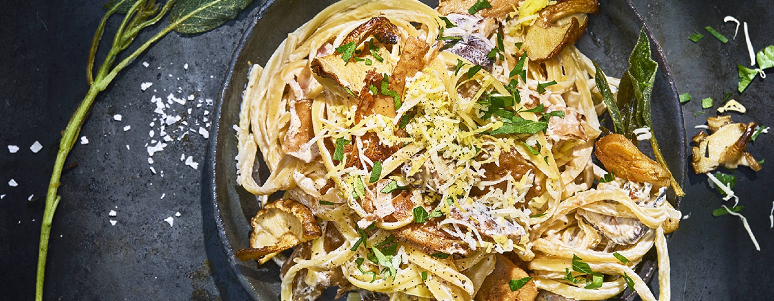Vegansk kycklingpasta i en svart djuptallrik på ett svart bord