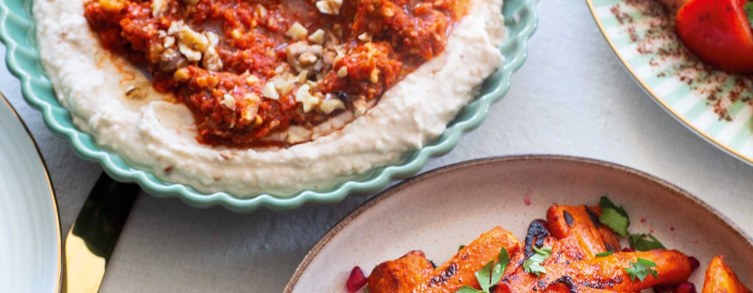 Harissarostade morötter på en tallrik bredvid en röra