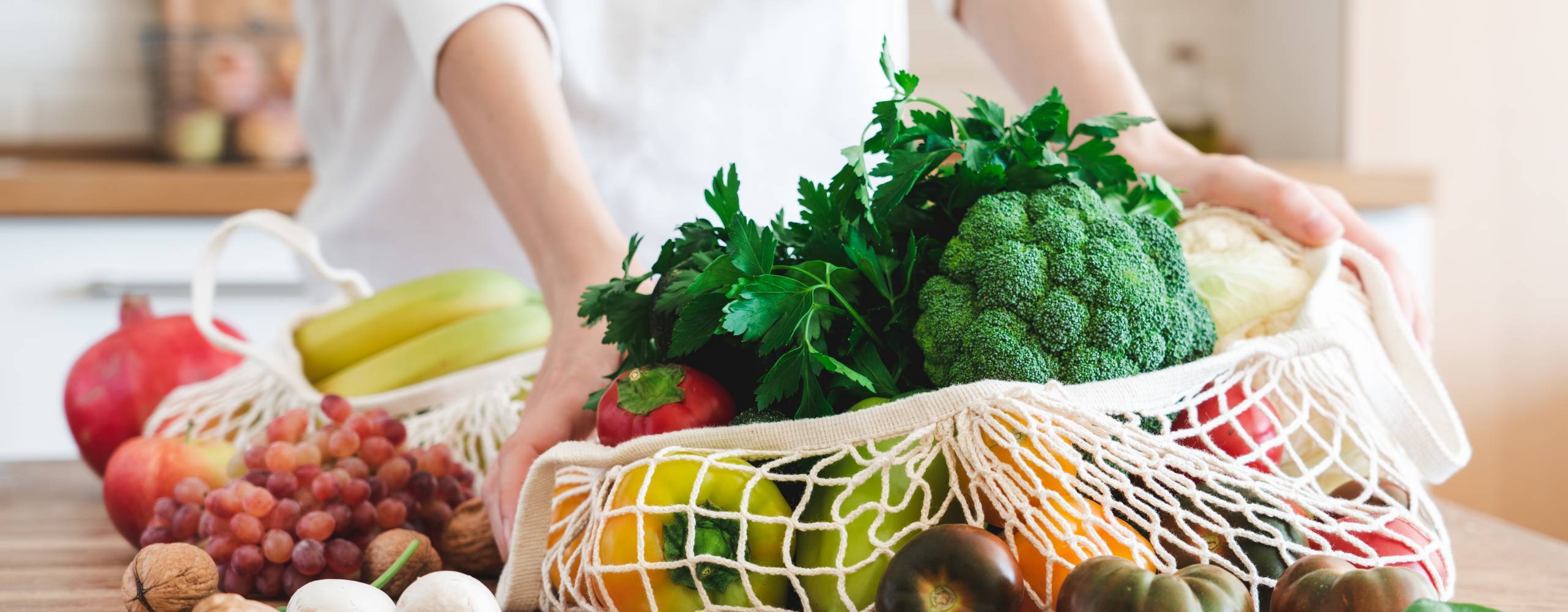 en matkasse i tyg på en träbänk med massa grönsaker i