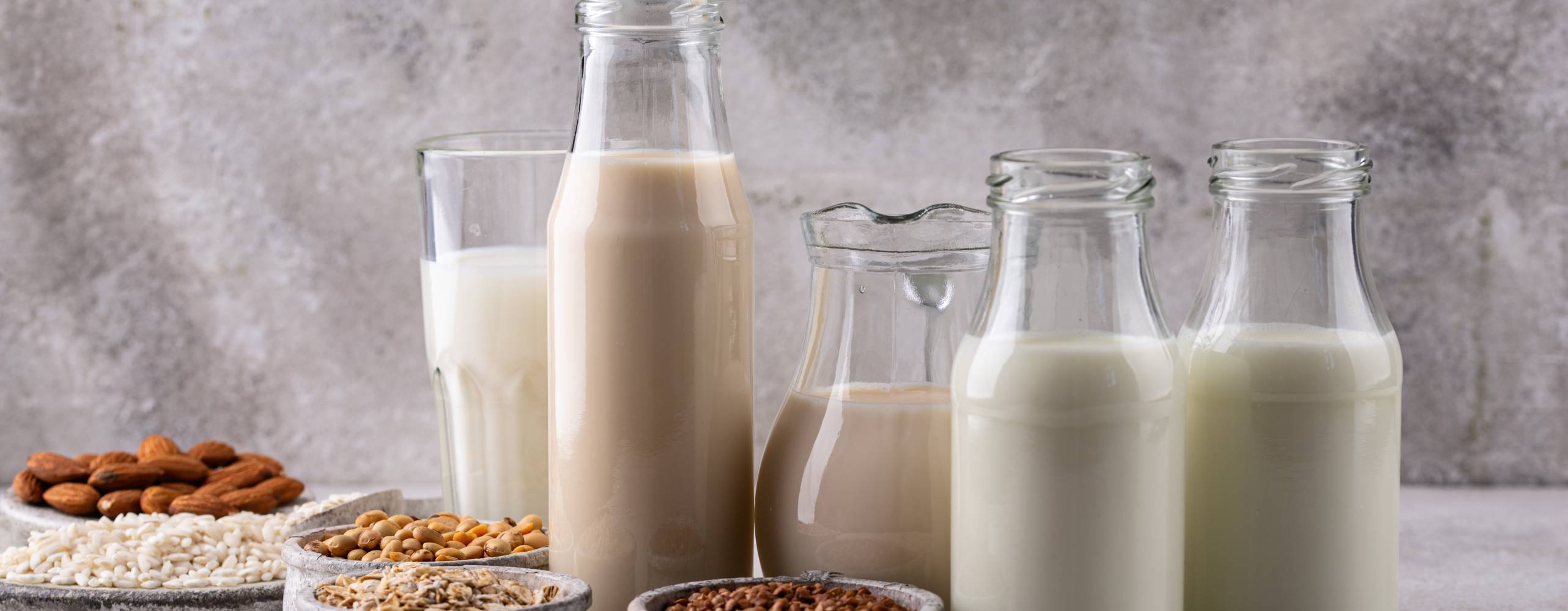 Fyra glasflaskor och ett glas med växtbaserad dryck