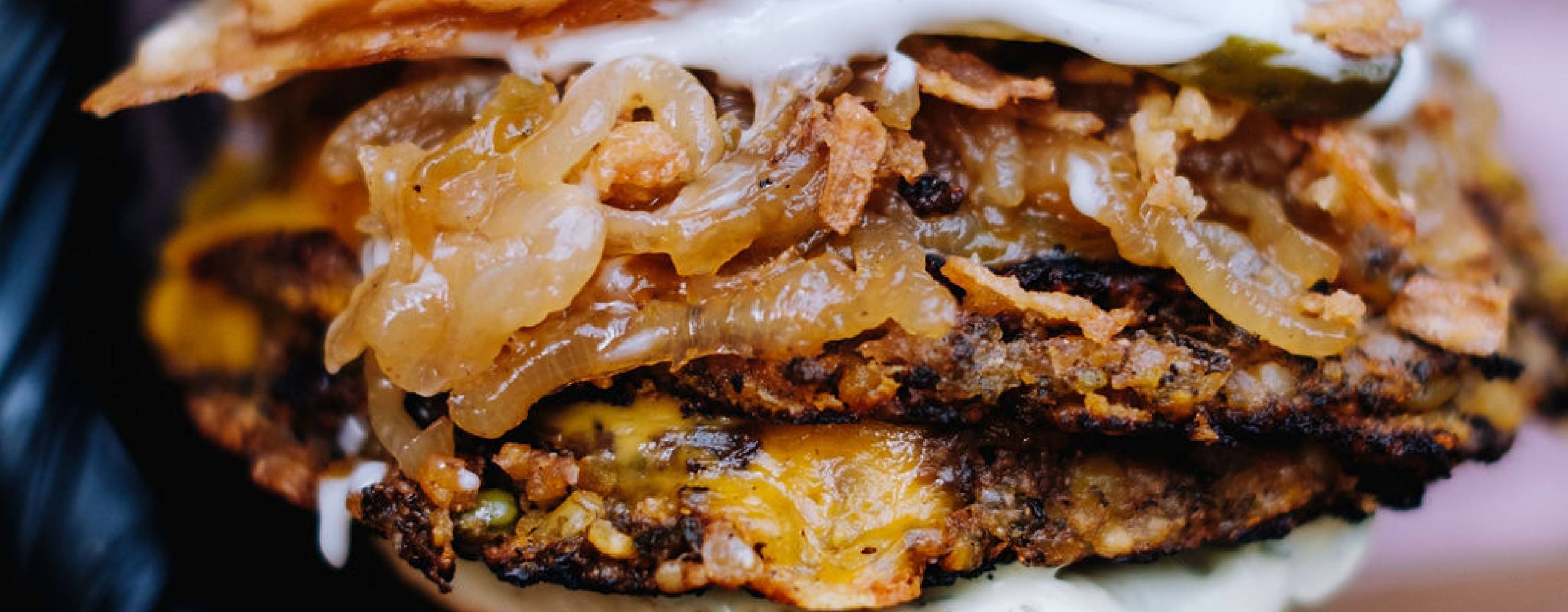 En hand med svarta handskar som håller i en växtbaserad burgare