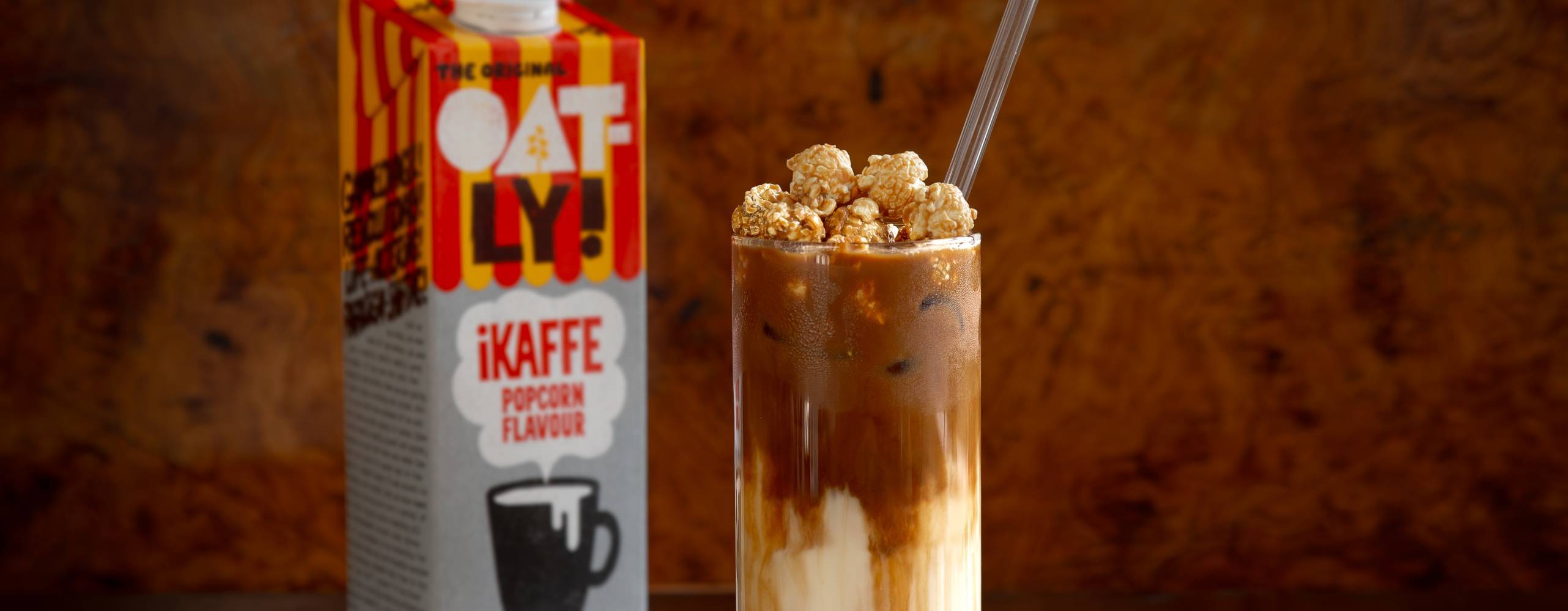 En förpackning havredryck bakom ett glas med en iskaffe på ett bord