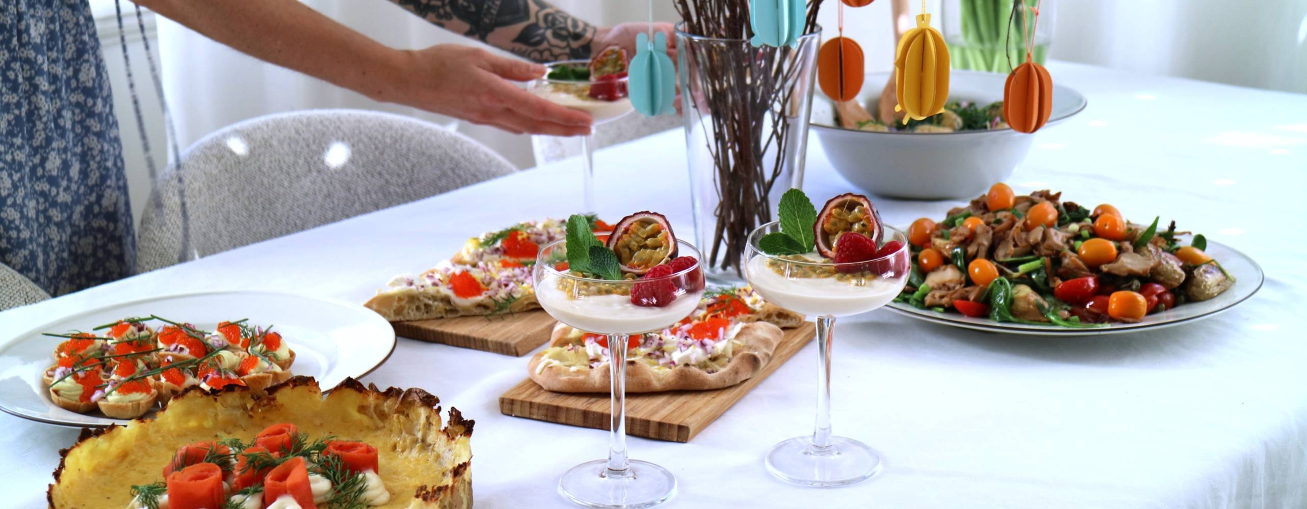 Veganskt påskbord och tjej med en tatuerad arm som håller i cocktailglas