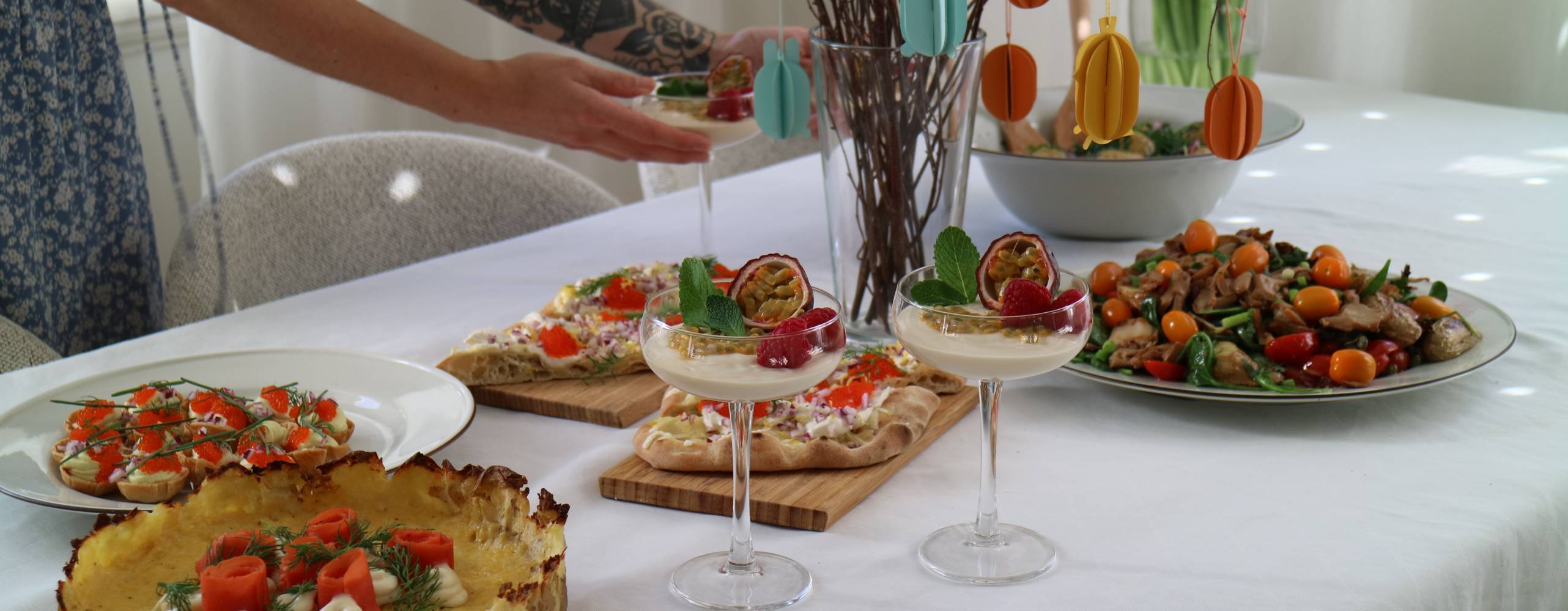 Veganskt påskbord och tjej med en tatuerad arm som håller i cocktailglas