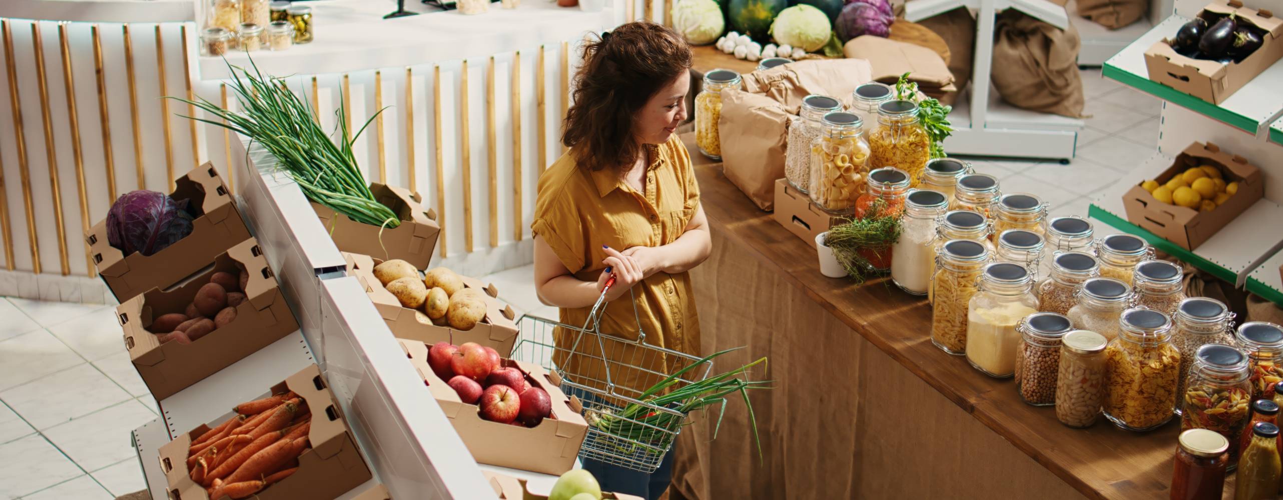 Zero waste store customer roaming around aisles adding healthy natural pantry staples to shopping basket, aerial drone shot. Local grocery shop client buying preservatives free bulk food items