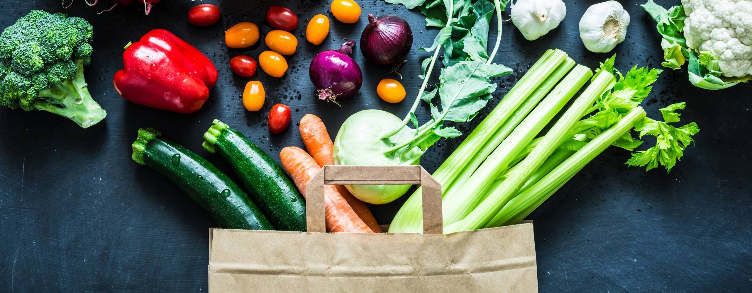 Bild på liggande matkasse där flera grönsaker ligger omkring