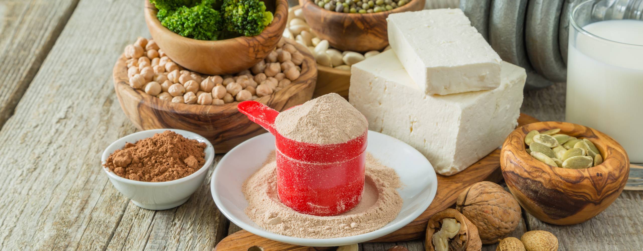 Bild på olika vegetabilsika proteinkällor och en träningsvikt i bakgrunden